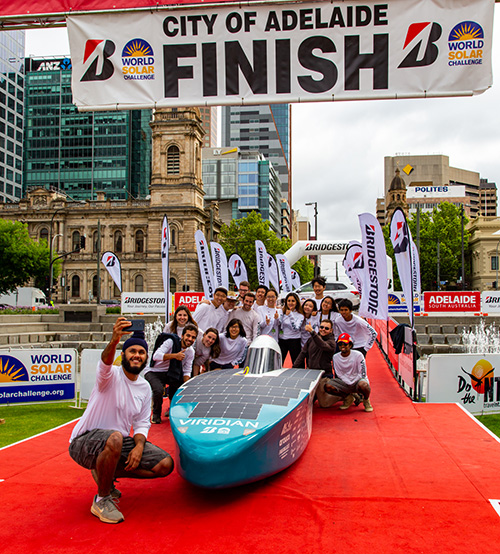 Blue Sky Solar Racing Team members posing with the solar car at the finish line in Adelaide, Australia.