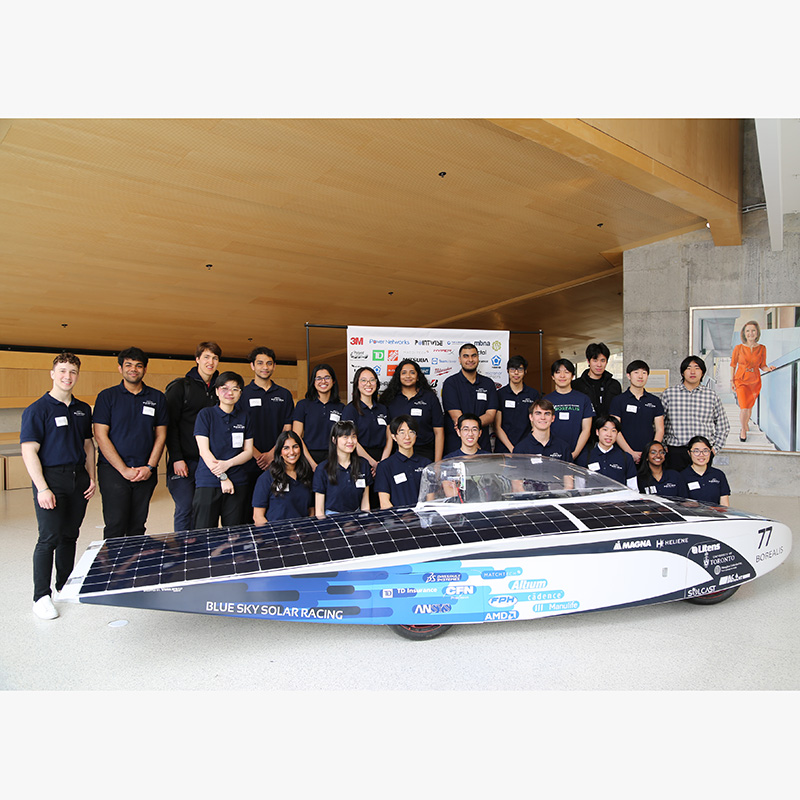 Blue Sky Solar Racing Team posing for a group photo behind the solar car, Borealis.